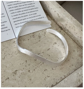 Macro shot of silver wave textured cuff bracelet on a minimalist stone tray