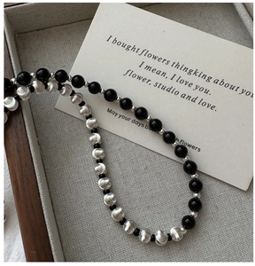 Macro detail of S925 silver necklace with black beads and brushed metal texture