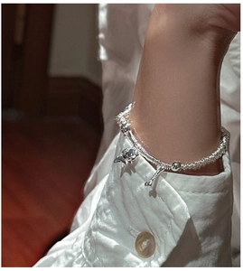 Macro detail of S925 sterling silver beaded bracelet with puppy and bone pendants