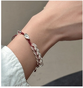 Détail d'un bracelet en cordon tressé rouge avec pièces en argent S925 et lingots
