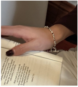 Detail of S925 silver beaded bracelet with OT clasp over an open book backdrop