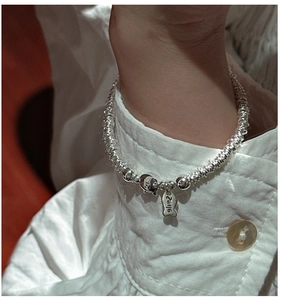 Detailed view of S925 silver bracelet featuring cute pig and fish charms on model