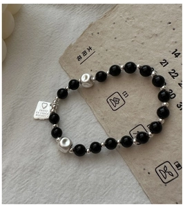 Dettaglio del bracciale in argento S925 con perle occhio di tigre e ciondolo con incisione