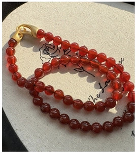 Detail of red carnelian bead necklace with an elegant matte gold S-hook clasp