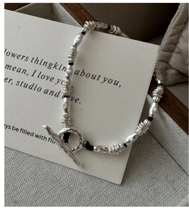 Detail of silver beaded bracelet with OT clasp and textured beads on aesthetic background