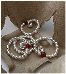 Close-up of S925 sterling silver beaded rings with red agate and heart charms