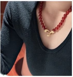 Detail view of a beaded red stone necklace with a textured gold-tone irregular clasp