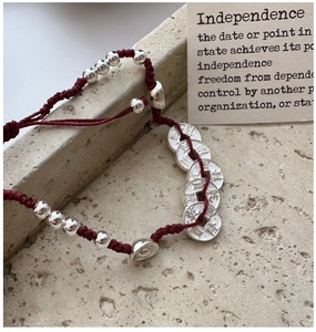 Gros plan de pièces en argent S925 sur un bracelet en corde tressée rouge ajustable
