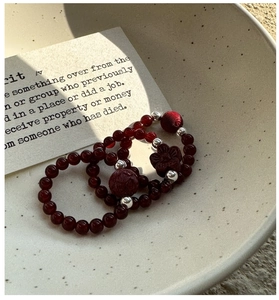 Detail of S925 silver red agate beaded rings with floral charm in a ceramic bowl