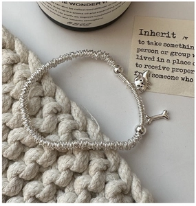 Detail of S925 sterling silver beaded puppy bracelet with bone charm on knit background