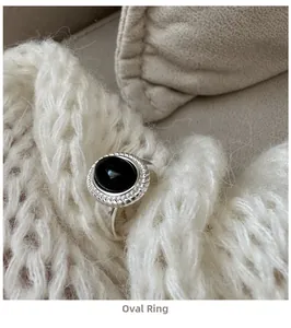 Close-up of vintage oval black onyx ring with silver twisted texture on a knit background