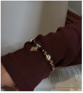 Dettaglio del bracciale con pietre occhio di tigre e ciondolo a cuore in argento al polso