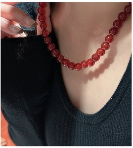 Close-up of a women's S925 silver beaded necklace featuring dark red translucent round beads
