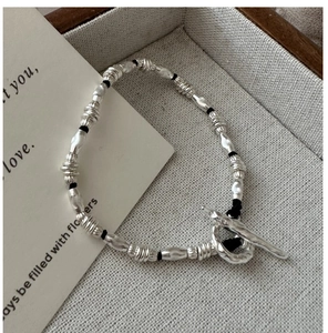 Detailed macro view of S925 silver beaded bracelet with OT toggle clasp on beige tray