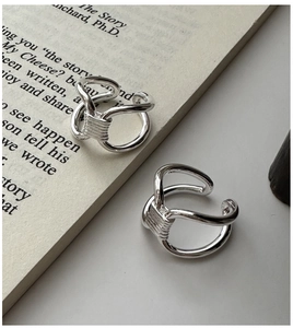 Dettaglio dell'anello d'argento a doppio strato su uno sfondo di libro minimalista