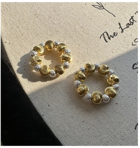 Macro view of textured gold and silver metal beads on earrings with elegant lighting