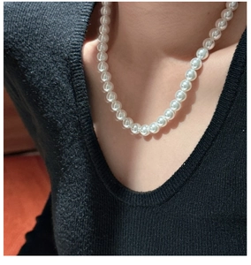 Detail of 8-10mm white round pearl beaded necklace on model with black V-neck top