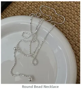 Detailed view of silver bead chain necklace displayed on a white ceramic plate