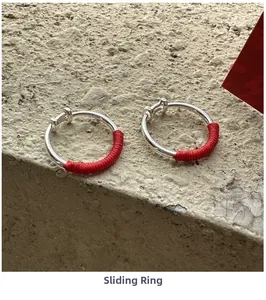 Detail of S925 silver adjustable rings with red braided rope on stone background