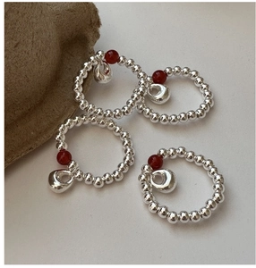 Macro detail of S925 sterling silver beaded rings with red agate and bean-shaped charms