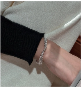 Gros plan d'un bracelet élastique en perles d'argent S925 porté au poignet d'une femme