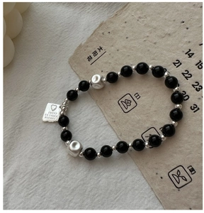 Dettaglio del bracciale in argento S925 con perle occhio di tigre e ciondolo inciso