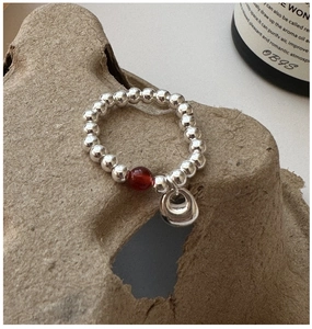 Detail of S925 sterling silver beaded ring with red agate bead and circular pendant charms