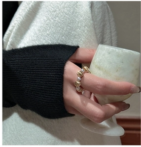 Detail of beaded ring with gold textured spheres and silver pave accents on a finger