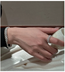 Vue détaillée des bagues et bracelet en perles d'argent portés sur la main