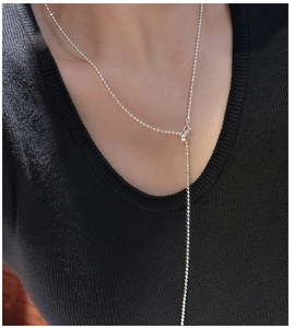 Macro detail of S925 silver beaded Y-necklace with adjustable sliding round clasp on black fabric