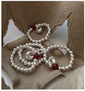 Detailed shot of S925 silver beaded rings with red agate charms and heart pendants