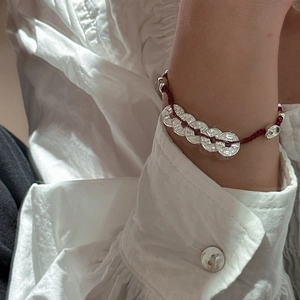 Bracelet S925 en corde rouge avec cinq pièces de monnaie porté au poignet d'un modèle