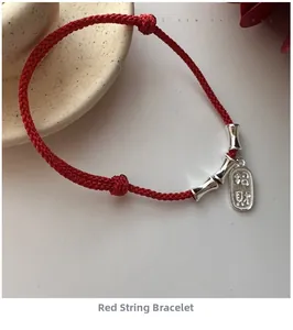 Detail of red cord bracelet featuring silver bamboo beads and Zhaocai pendant