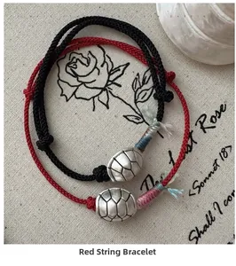 Detailed view of woven red and black bracelets with vintage silver tortoise shell pendants