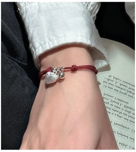 Detailed close-up of a red string bracelet with S925 silver heart and bead charms