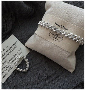 Détail d'un bracelet et d'une bague en argent S925 avec perles sur un coussin en lin
