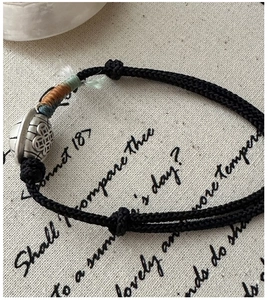 Macro shot of handcrafted black braided cord bracelet with silver bead and ethnic thread