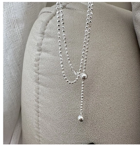 Detail of adjustable silver beaded necklace with pull-string bead and drop pendant detail