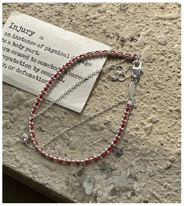 Detail of red woven bracelet showing S925 sterling silver lobster clasp and logo