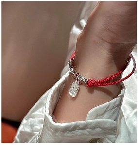 Close-up of red woven rope bracelet with S999 sterling silver bamboo charms and tag