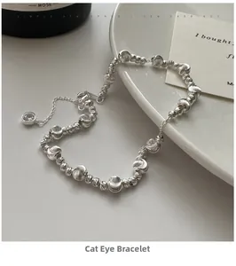 Detail of silver cat-eye bead bracelet with lobster clasp and clear stone pendant