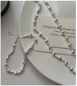 Macro shot of faceted silver beaded bracelet and necklace with reflective metallic texture