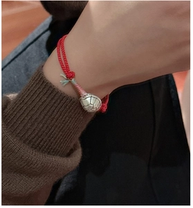 Close-up of S925 silver tortoise shell charm on a red braided string bracelet