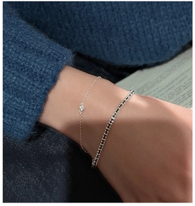 Detail of S925 silver minimalist zircon bracelet and black-white beaded chain on wrist