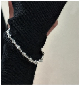 Detail of S925 sterling silver beaded bracelet with cat-eye facets on a black sweater