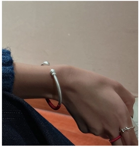 Détail d'un bracelet jonc ouvert en argent S925 et bague assortie avec cordon tressé rouge