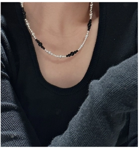 Close-up of S925 silver beaded necklace with black agate beads on a black sweater