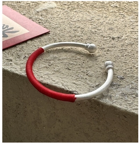 Détail macro du bracelet jonc en argent S925 avec des accents de fils de soie rouge tressés