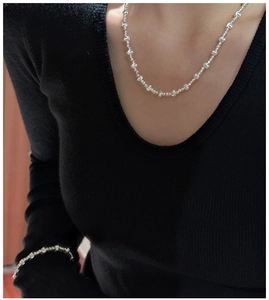 Detail view of S925 sterling silver beaded necklace and bracelet set on a female model