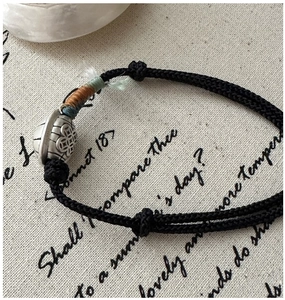 Detail of handmade black braided rope bracelet with engraved silver turtle shell bead